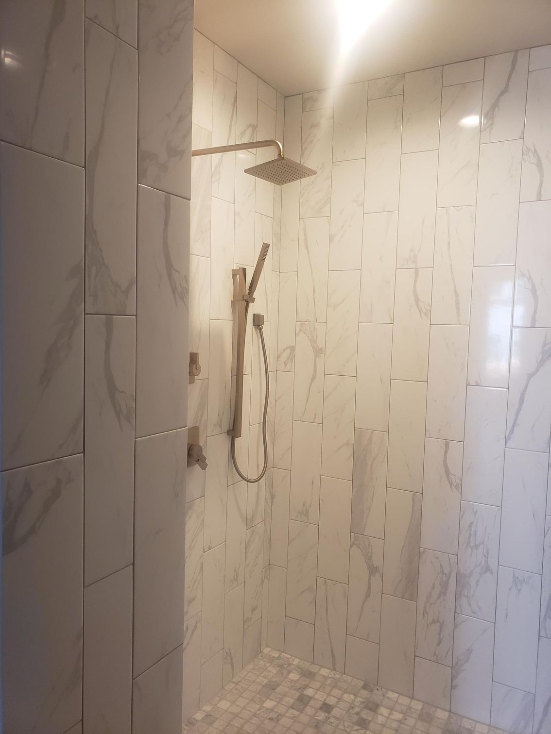 A shower with white tiles and a shower head.