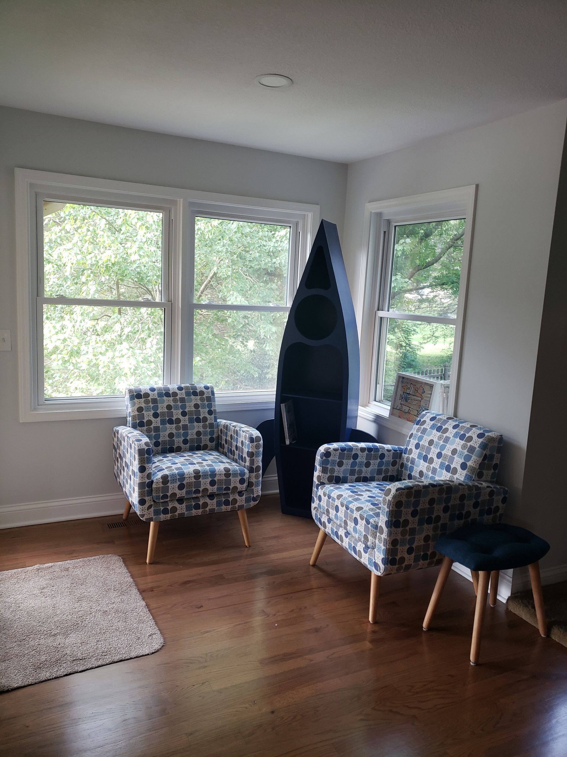 A living room with two chairs and a boat in the background.