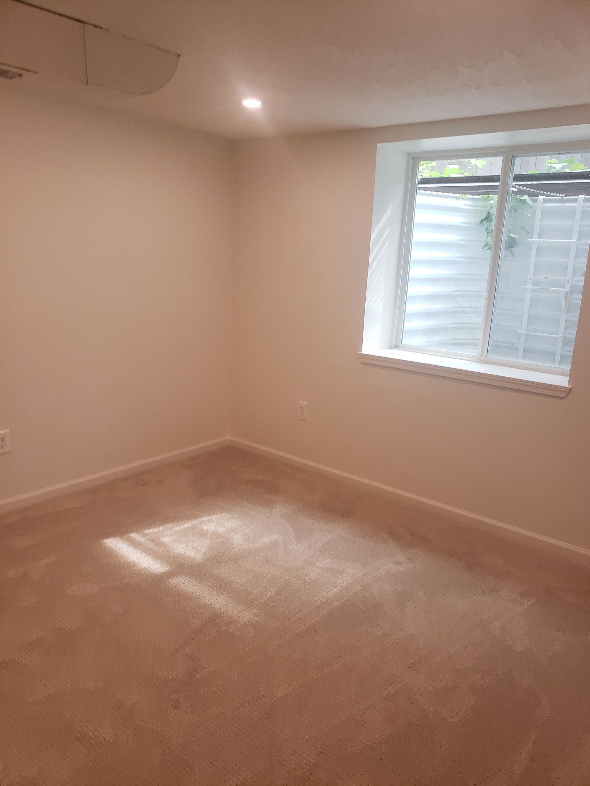 An empty room with a window and a carpeted floor.