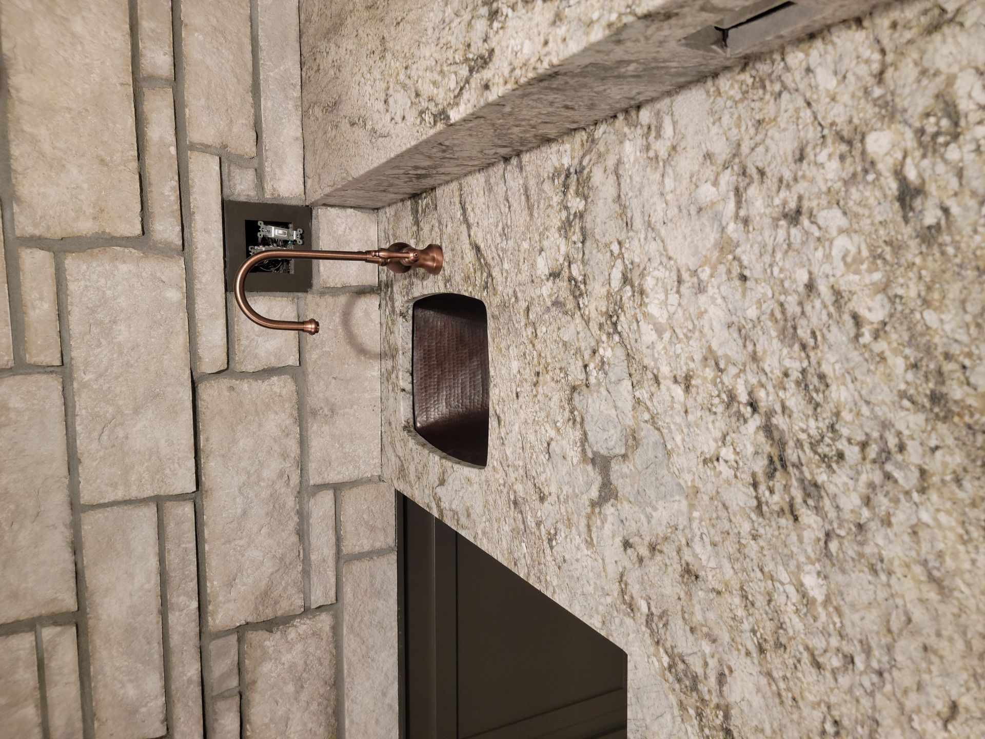 A brick wall with a copper pipe hanging from it.