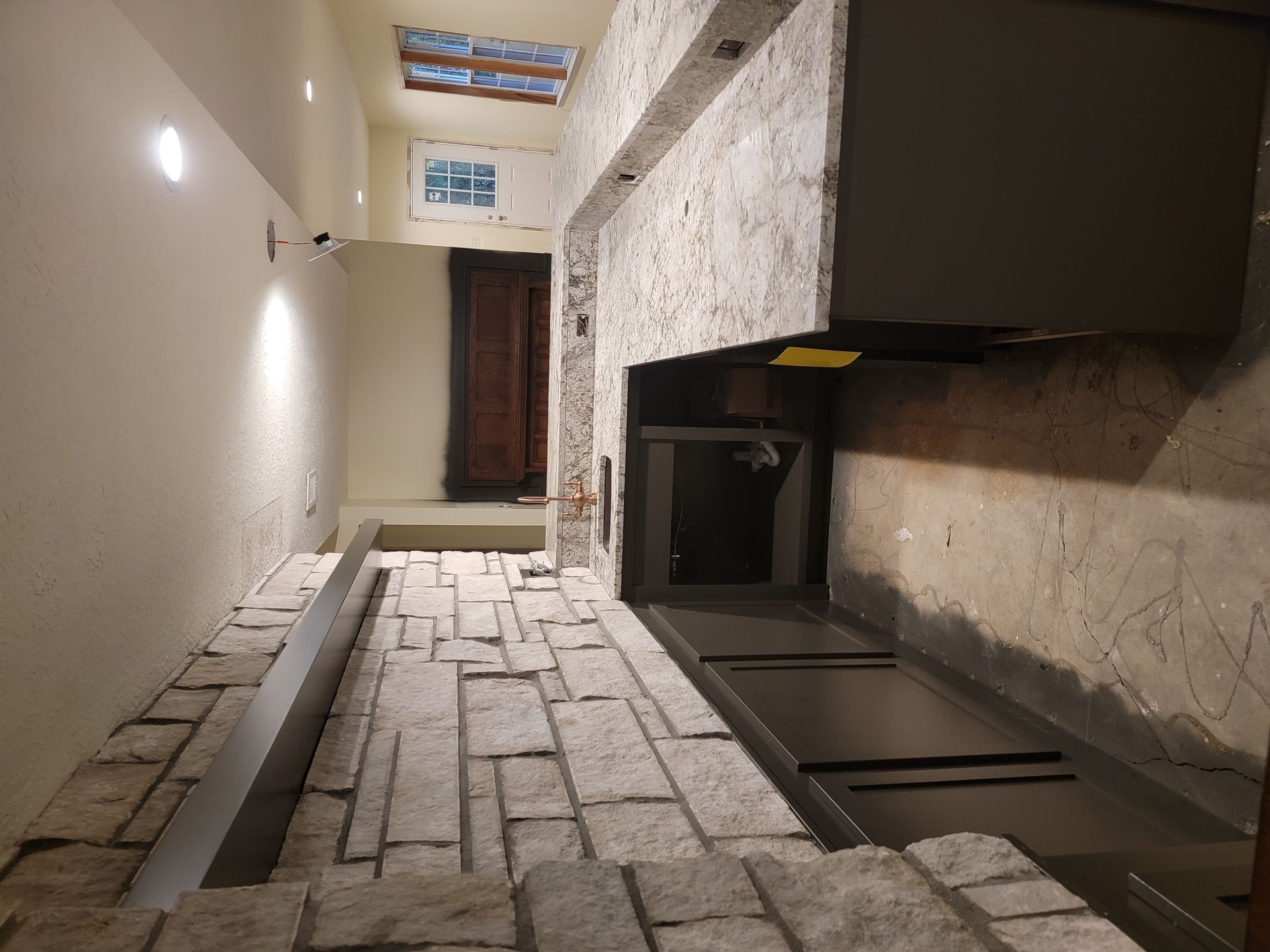 A narrow hallway with a stone fireplace in the middle