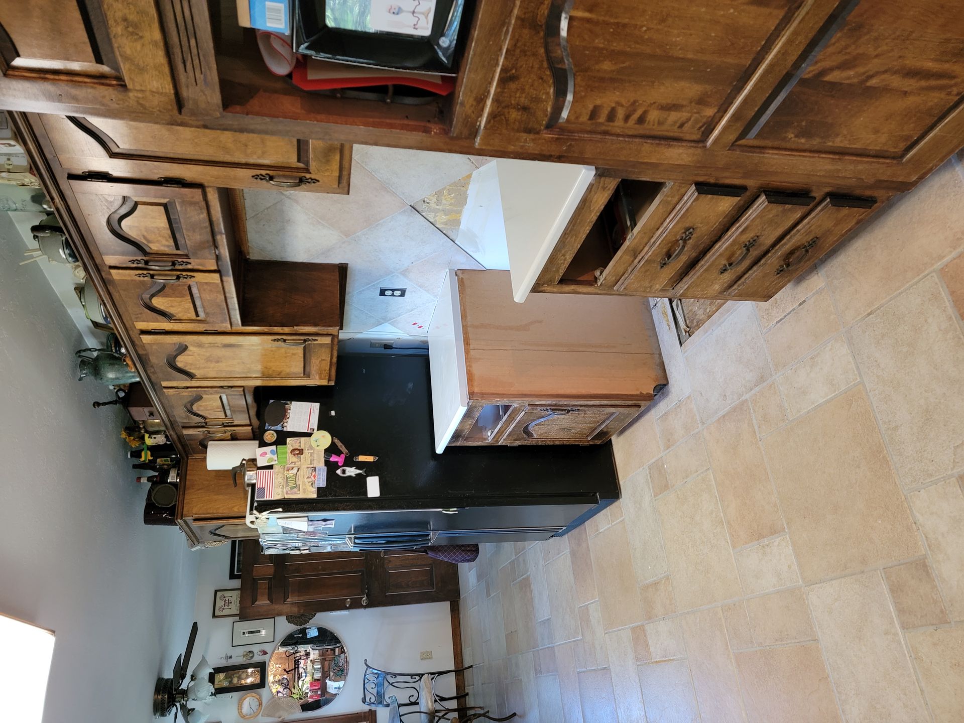 A kitchen with wooden cabinets and a black refrigerator