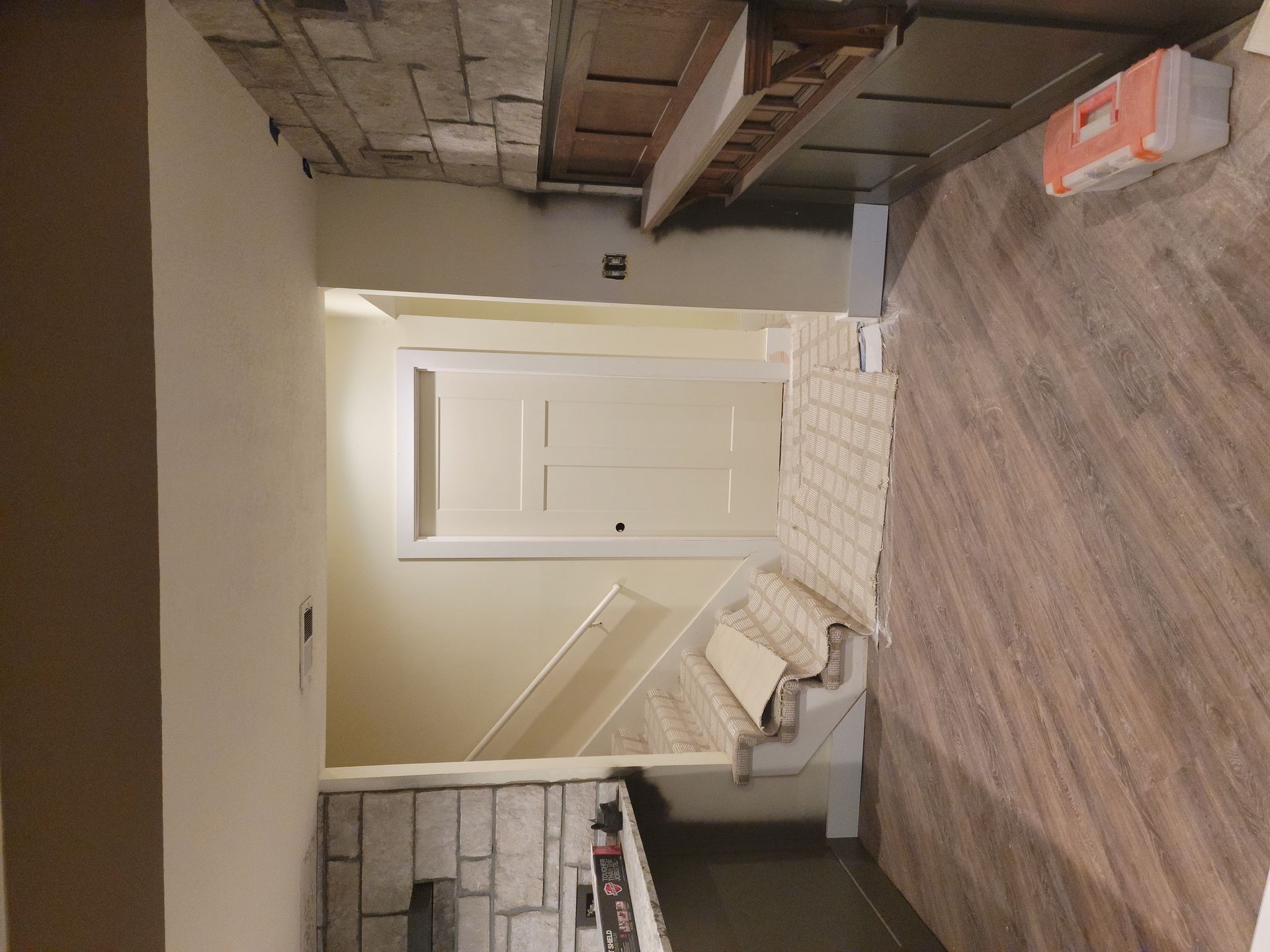 A room with a wooden floor , stairs and a fireplace.