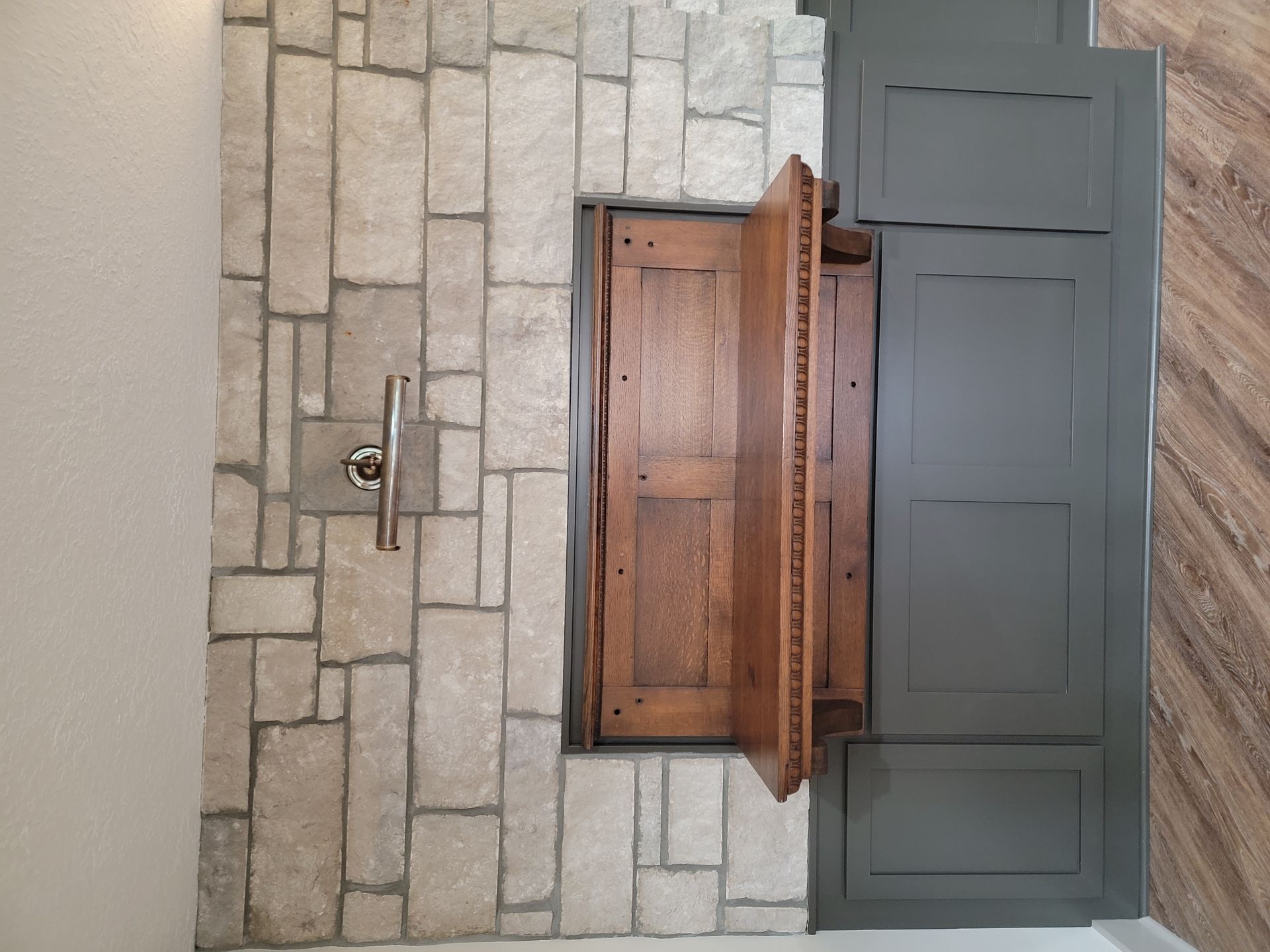 A fireplace with a wooden mantle and a stone wall