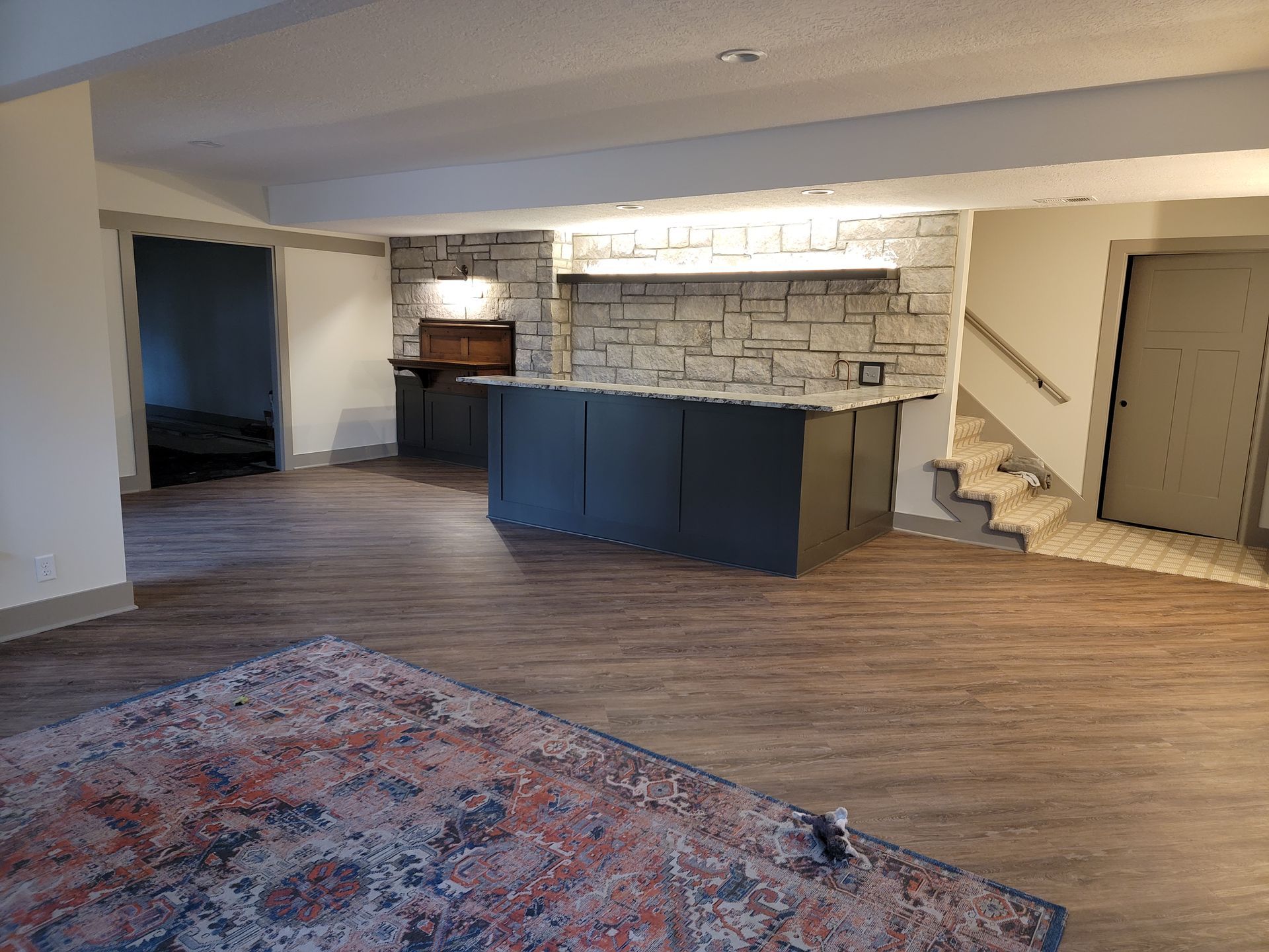 A basement with a bar and stairs in it.