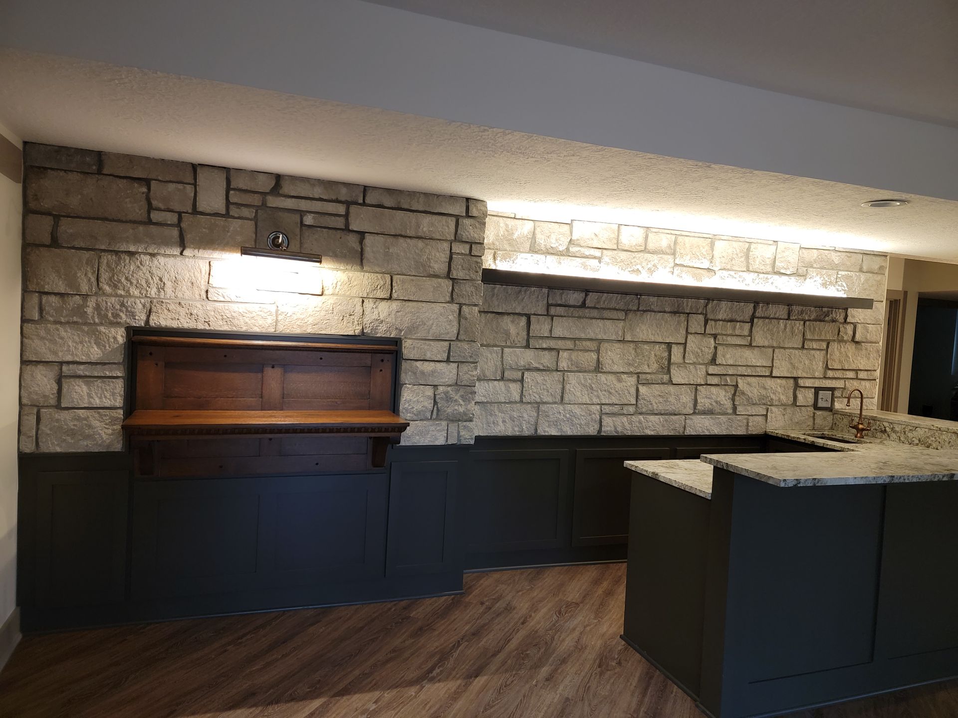 A kitchen with a stone wall and a wooden counter top.