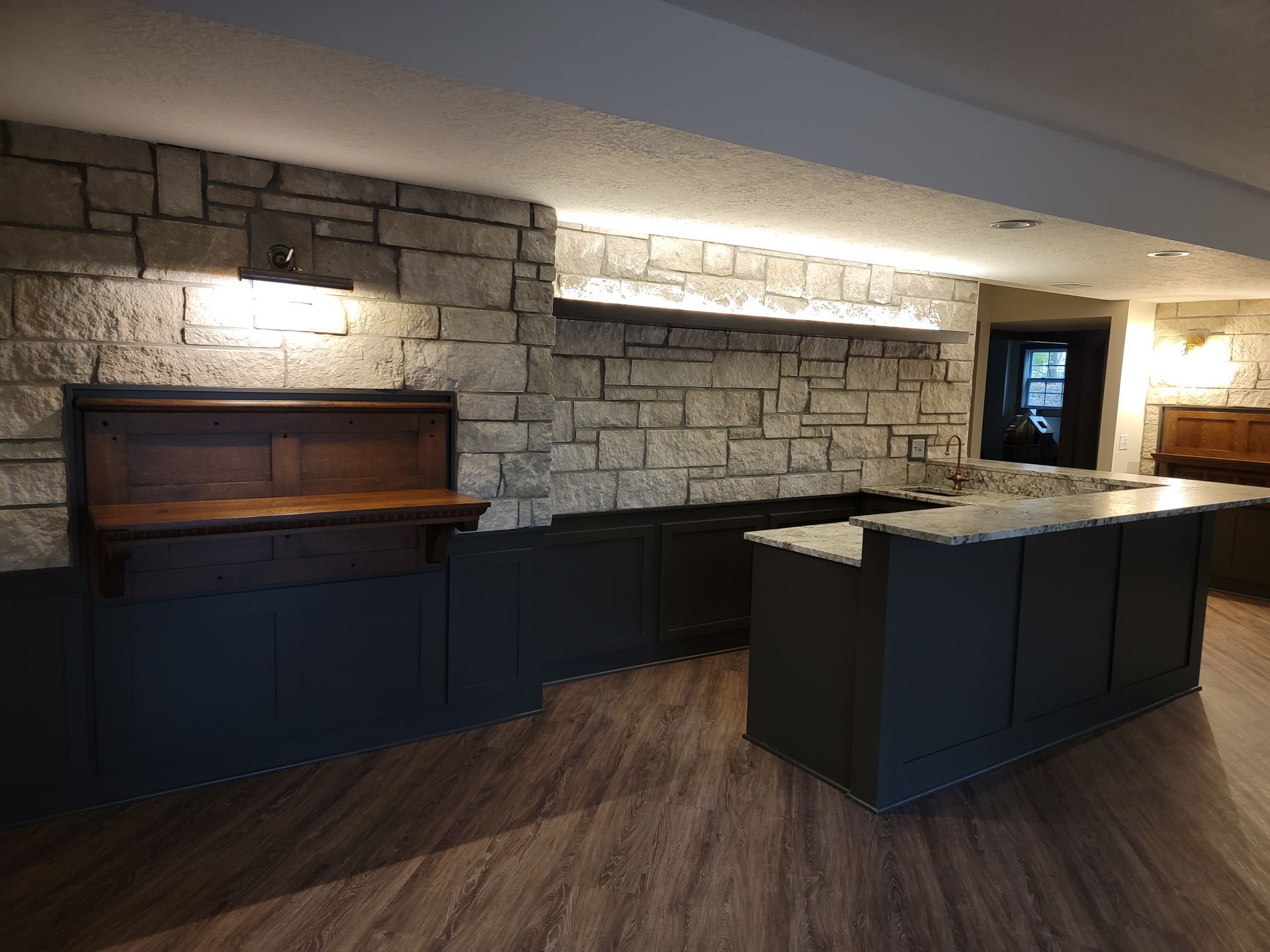 A kitchen with a stone wall and a wooden counter top.