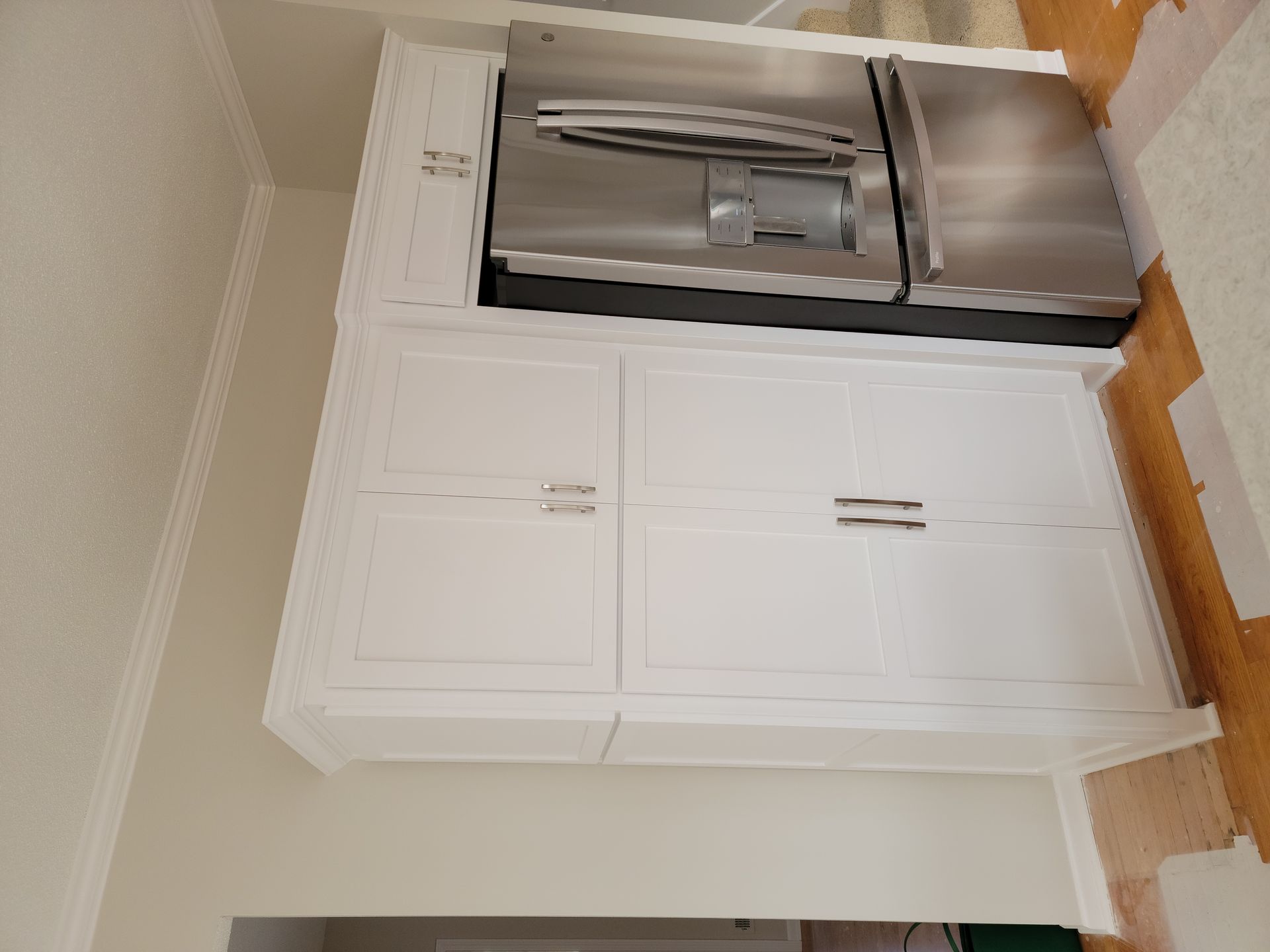 A kitchen with white cabinets and a stainless steel refrigerator.