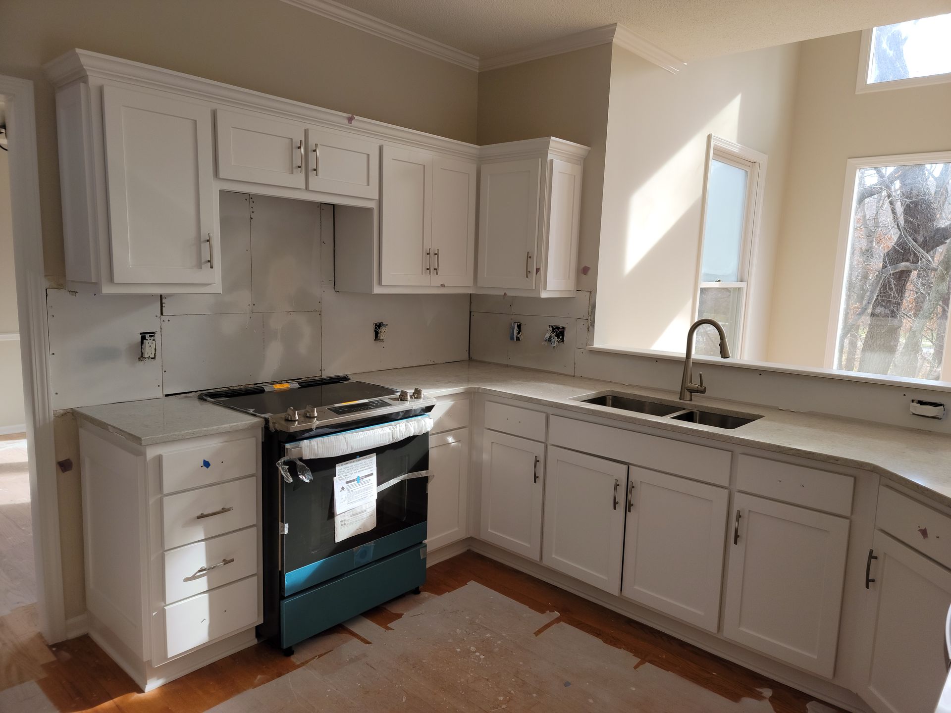 A kitchen with white cabinets , a stove and a sink.