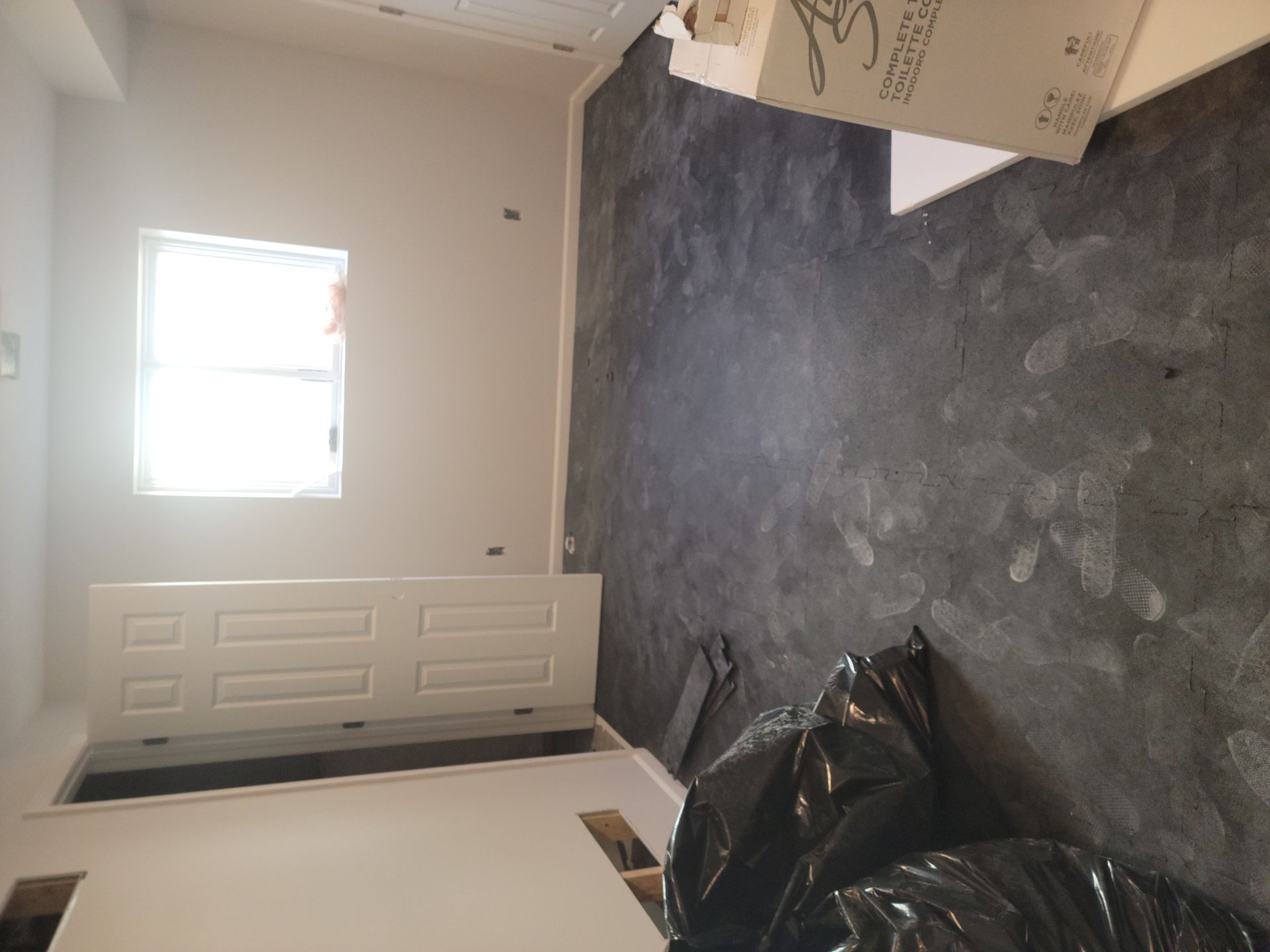 A room with a window and a black bag on the floor.