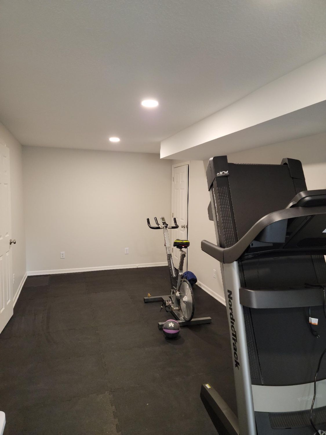 There is a treadmill and a bike in the room.