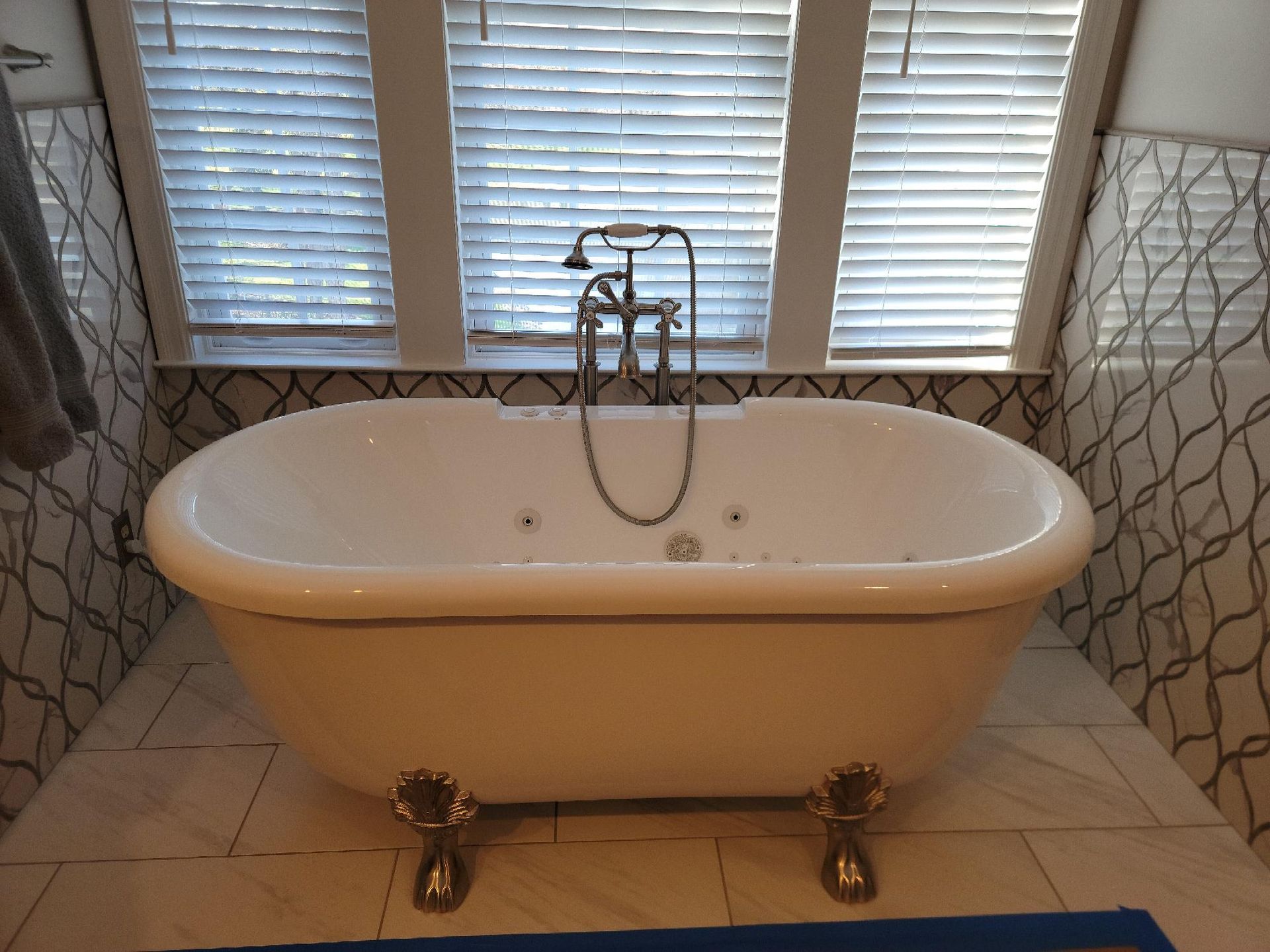 A bathtub in a bathroom with blinds on the windows