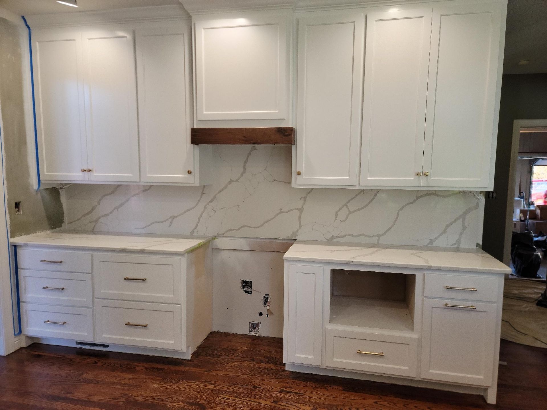 A kitchen with white cabinets and marble counter tops is being remodeled.
