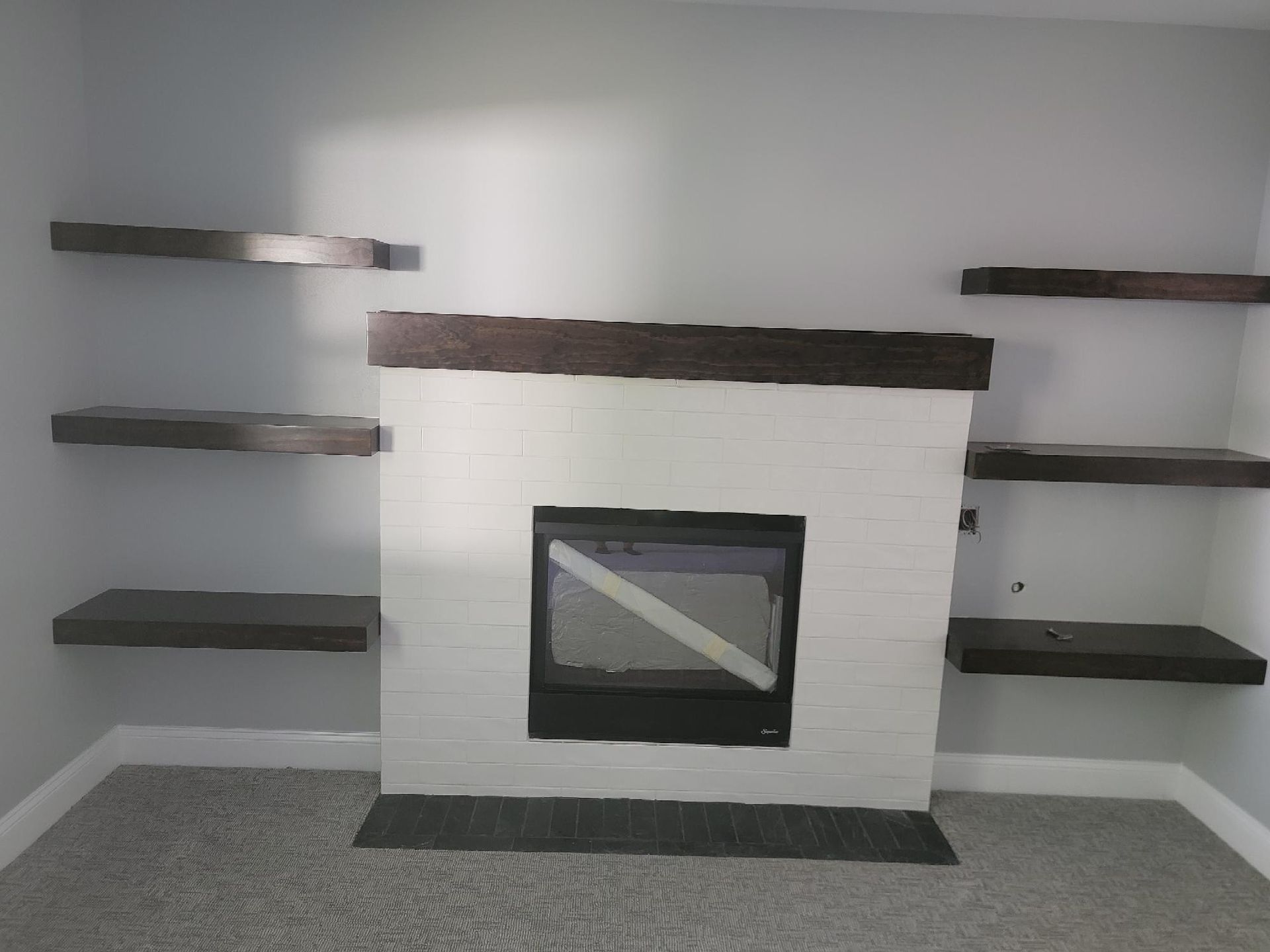 A living room with a fireplace and shelves.