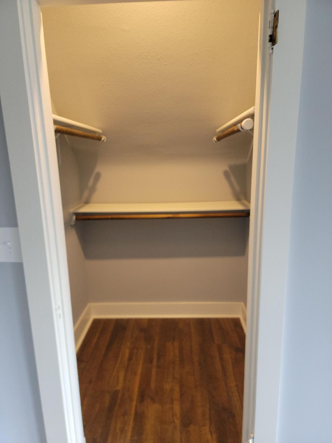 A walk in closet with wooden floors and shelves.