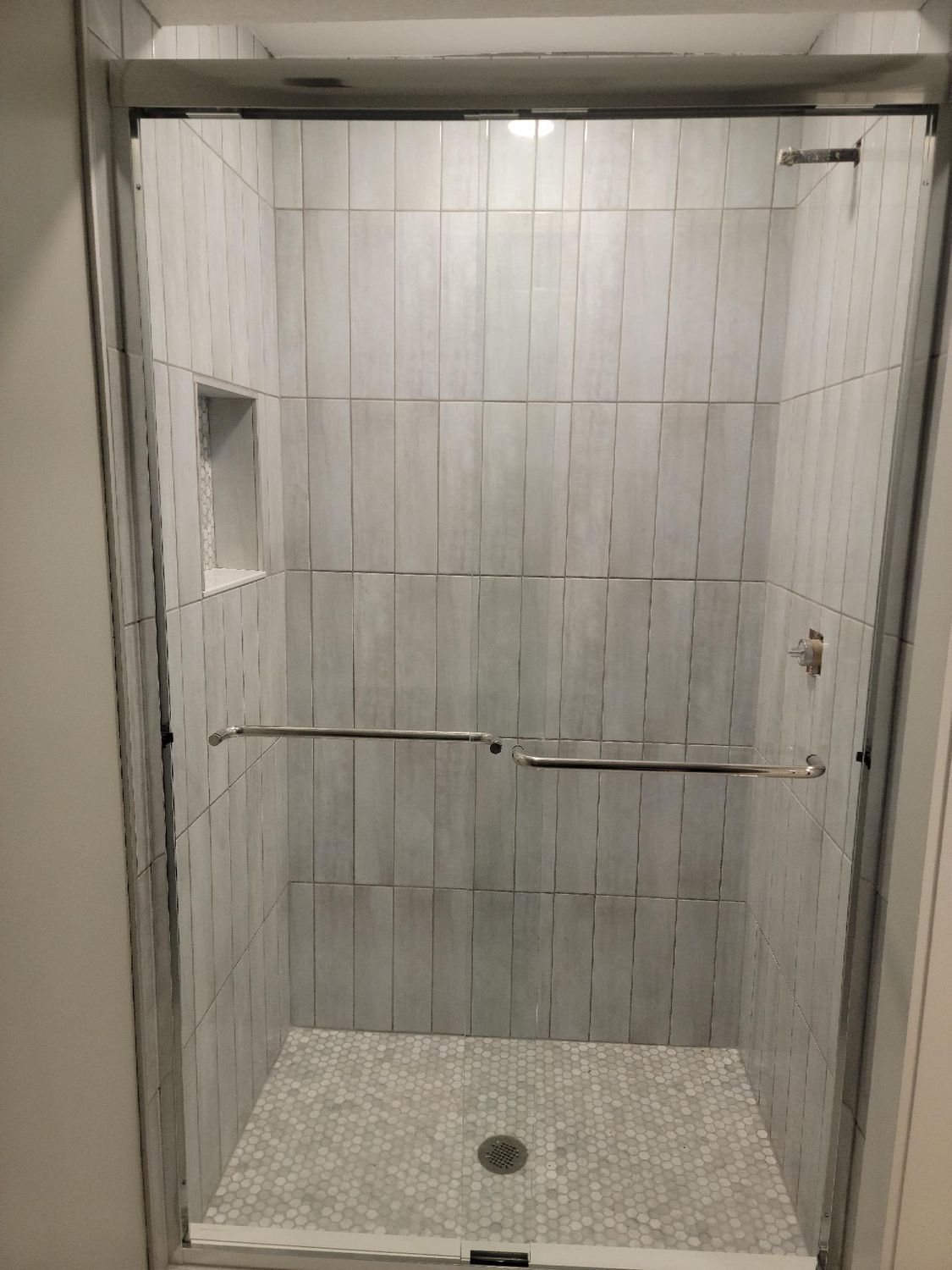A shower stall with a glass door and a tiled wall.