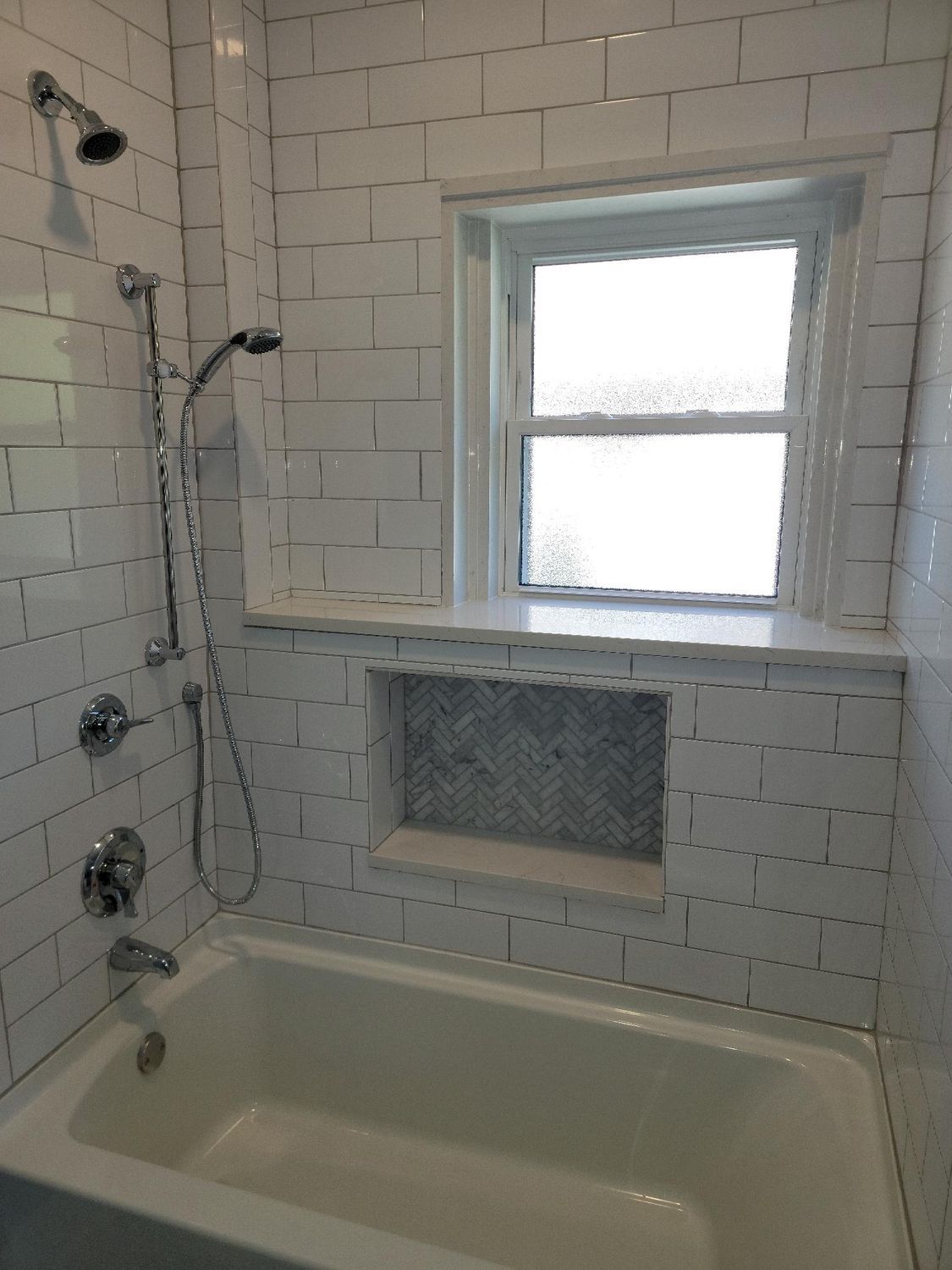 A bathroom with a tub , shower and window