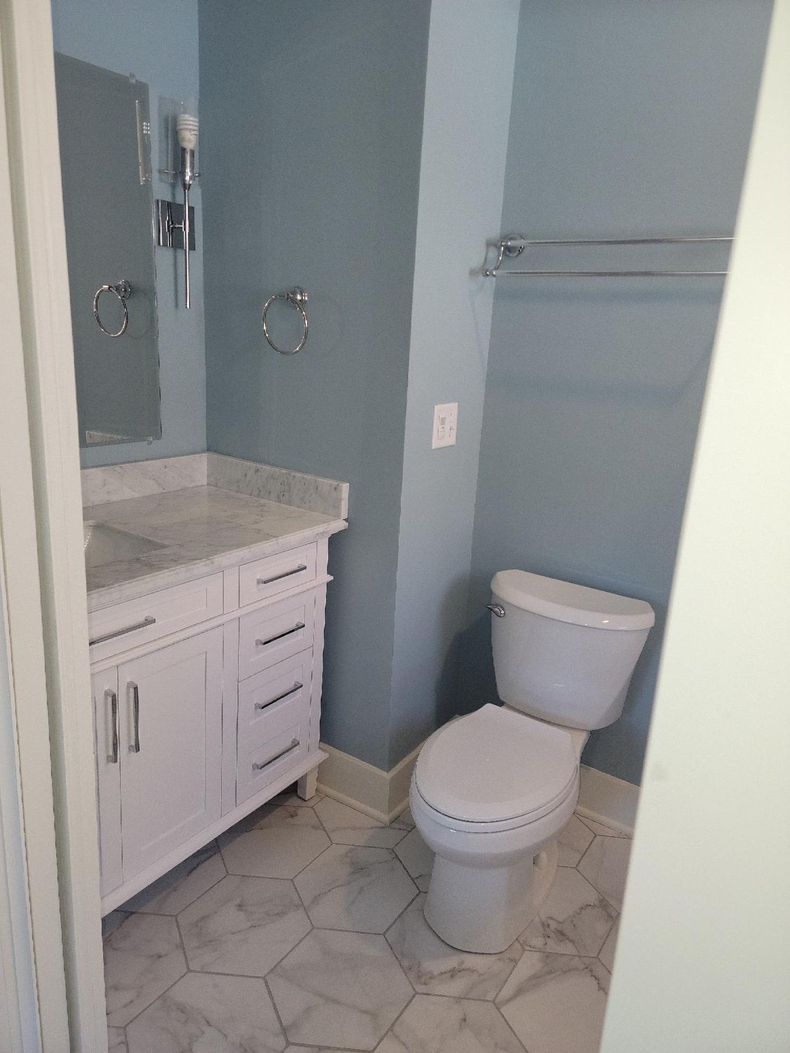 A bathroom with a toilet , sink and mirror.