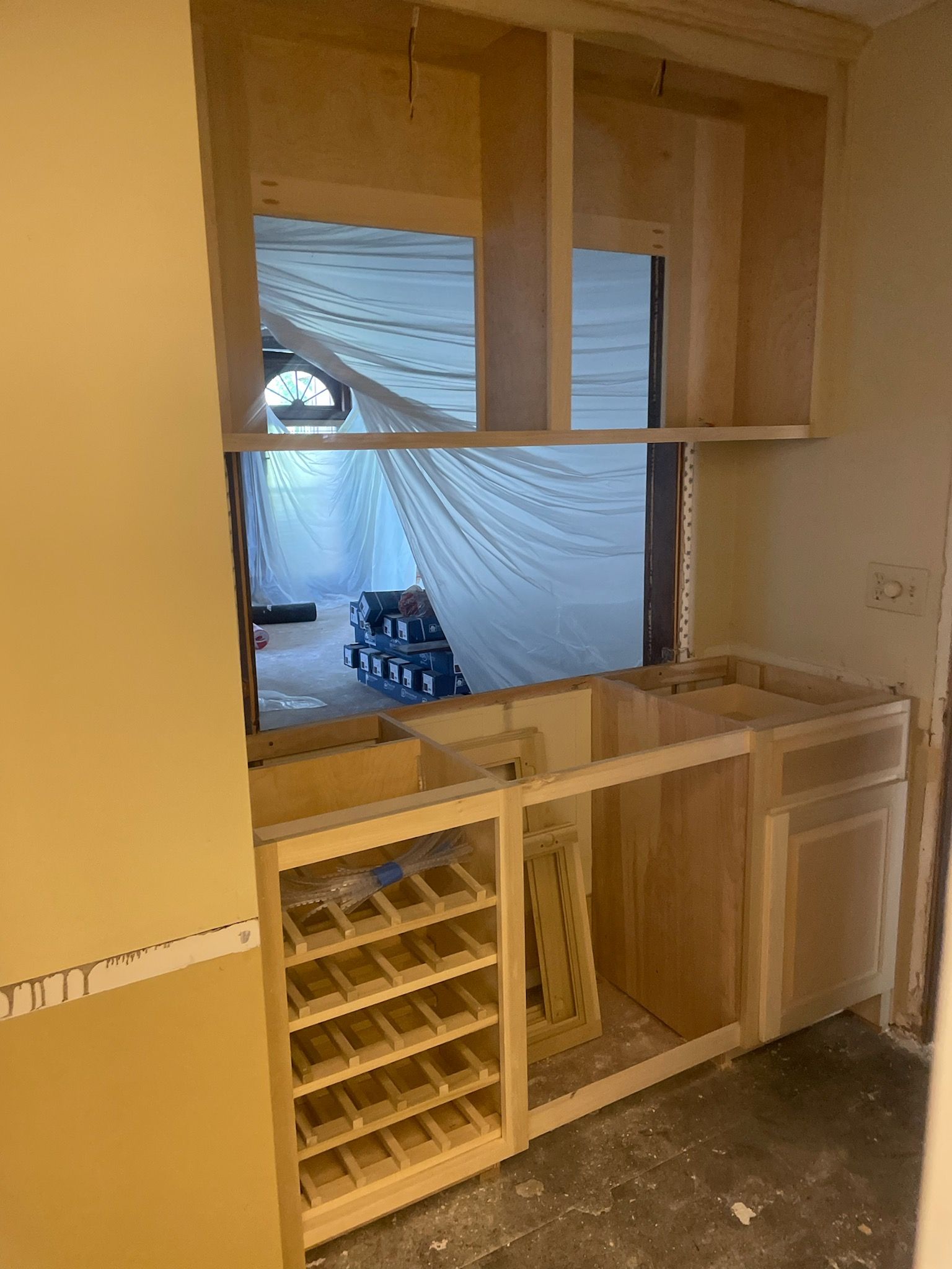 A kitchen under construction with wooden cabinets and a wine rack.