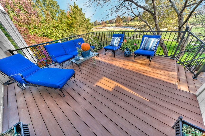 A wooden deck with blue chairs and a couch
