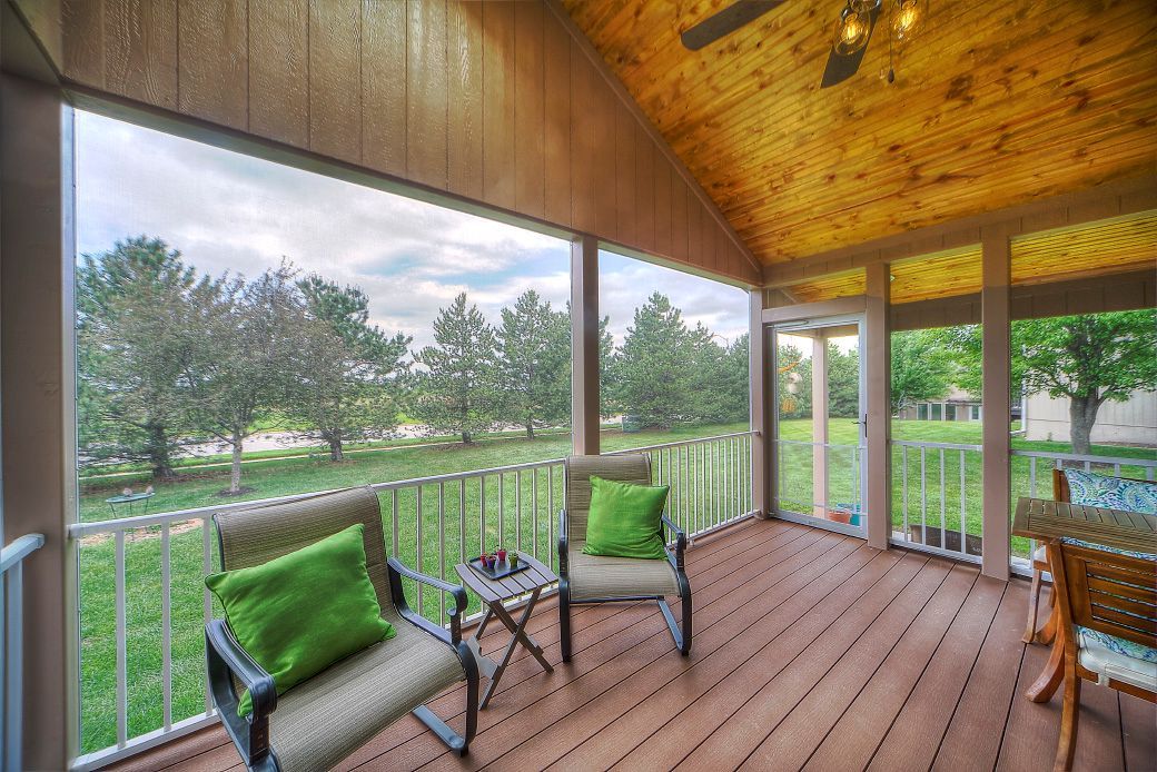 A screened in porch with two chairs and a table.
