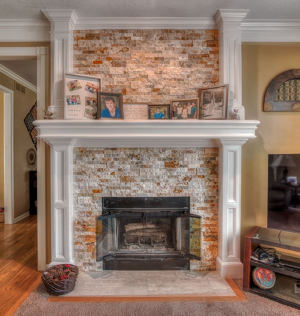 A living room with a fireplace and pictures on the mantle
