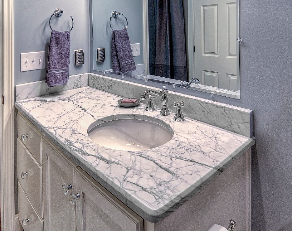 A bathroom with a marble counter top and a sink