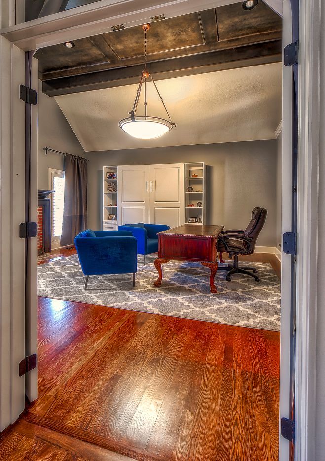 A living room with a desk , chairs , and a rug.