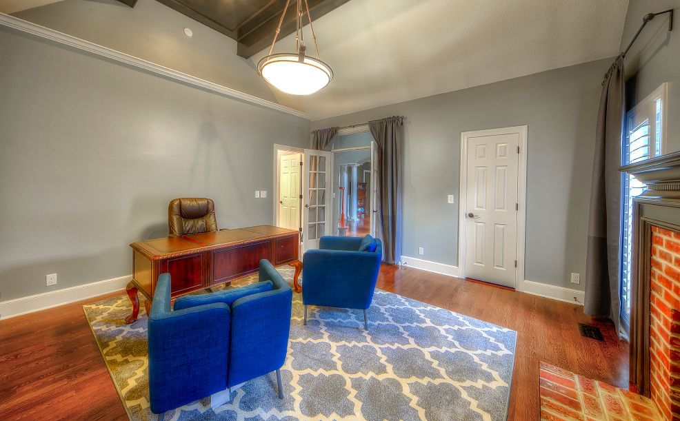 A living room with a desk , chairs , and a fireplace.