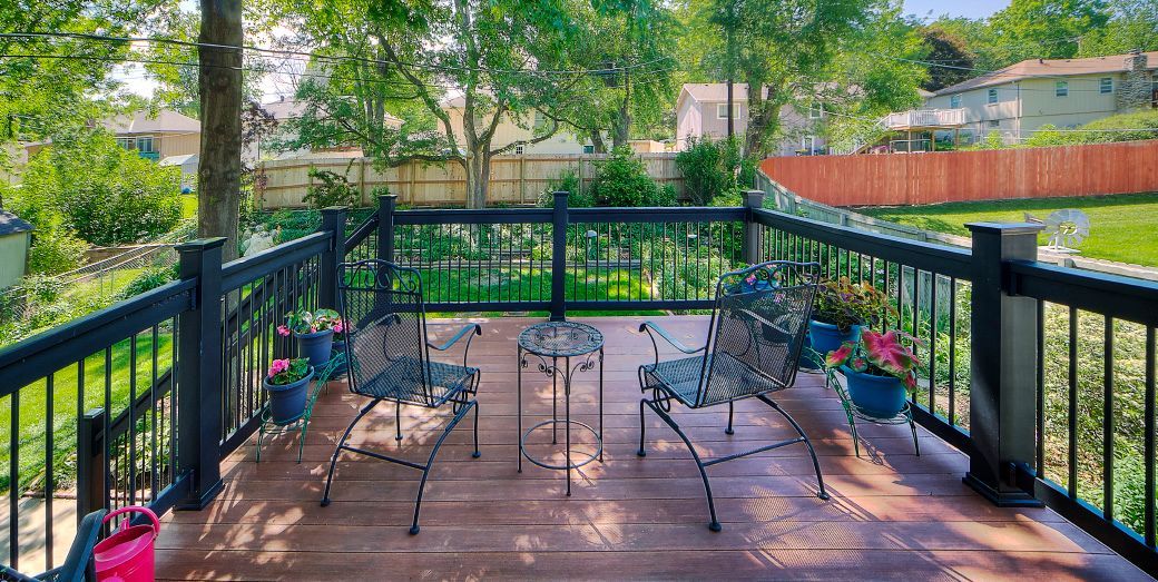 A deck with a black railing and a table and chairs on it.