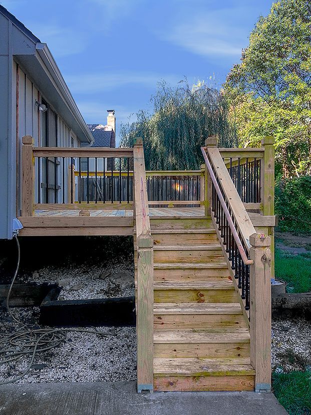 A wooden deck with stairs leading up to it next to a house.