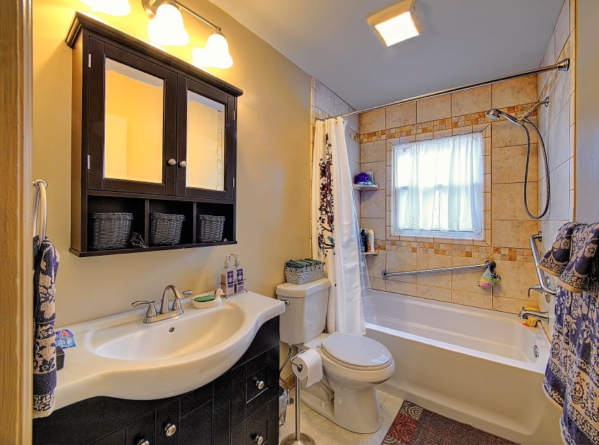 A bathroom with a sink , toilet , tub and window