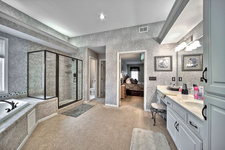 A large bathroom with a tub , sink , mirror and walk in shower.