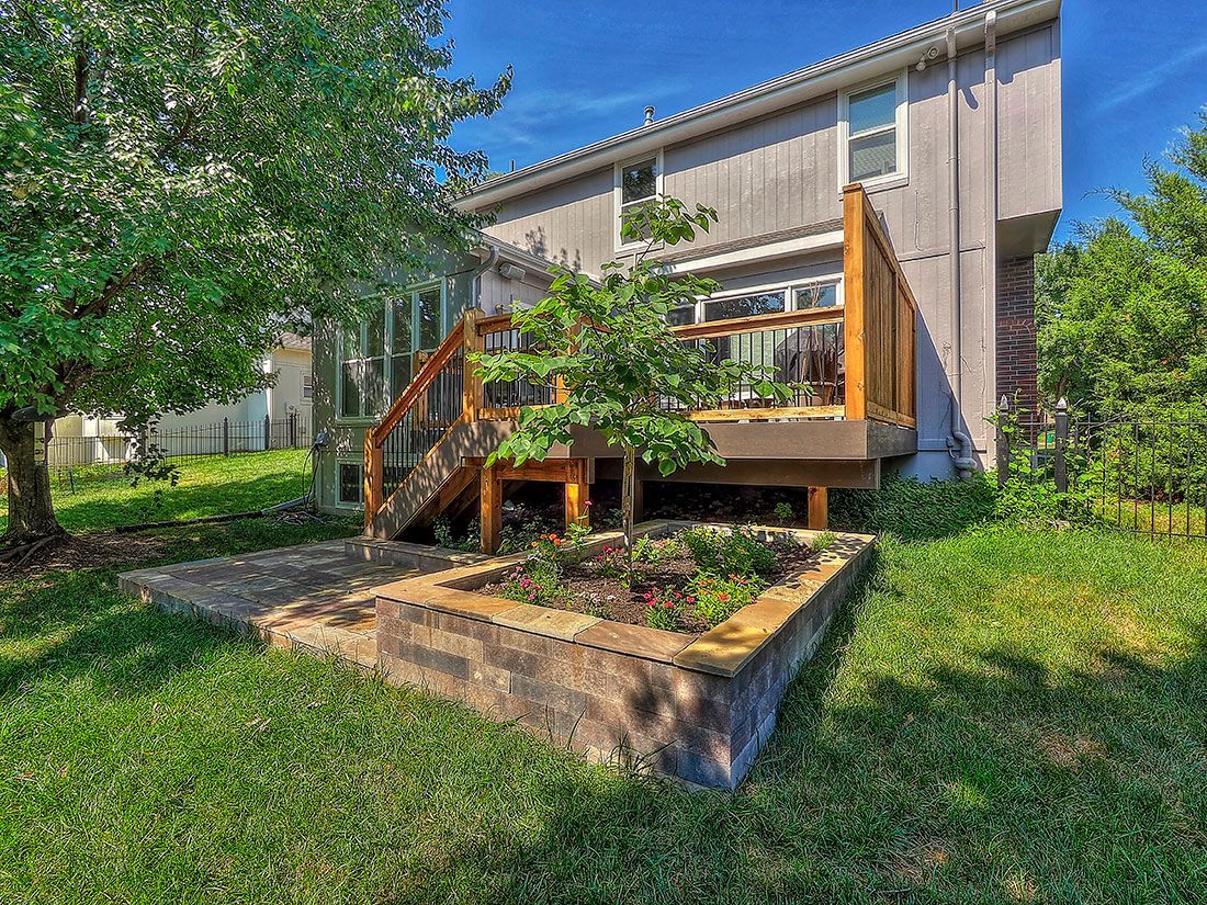 The backyard of a house with a wooden deck and stairs.