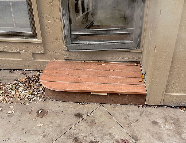 A wooden step leading to a sliding glass door