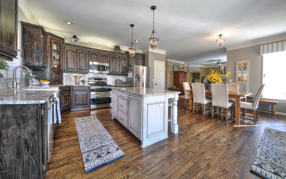 A kitchen and dining room in a house with hardwood floors and stainless steel appliances.