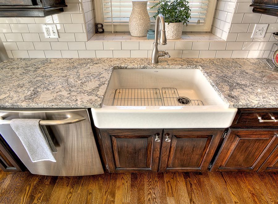 A kitchen with a white sink and a stainless steel dishwasher