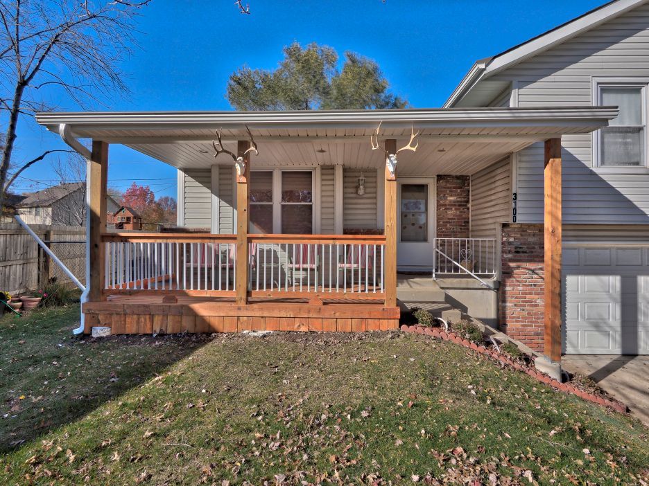 The front of a house with a large porch and a wooden deck.