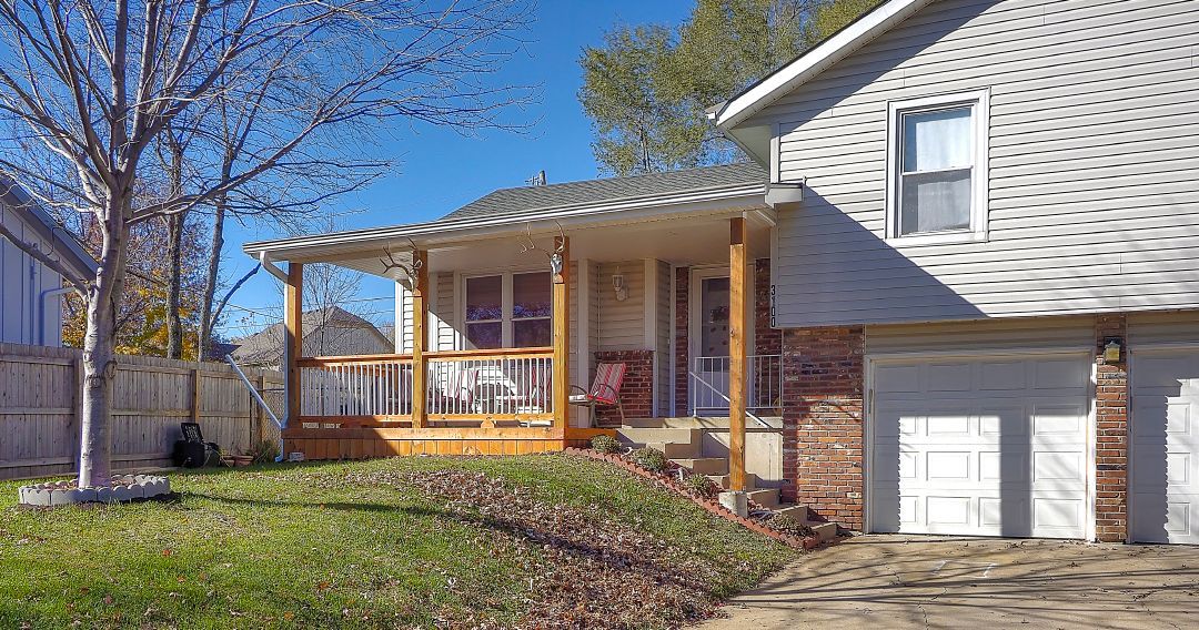 A house with a porch and a garage is for sale.