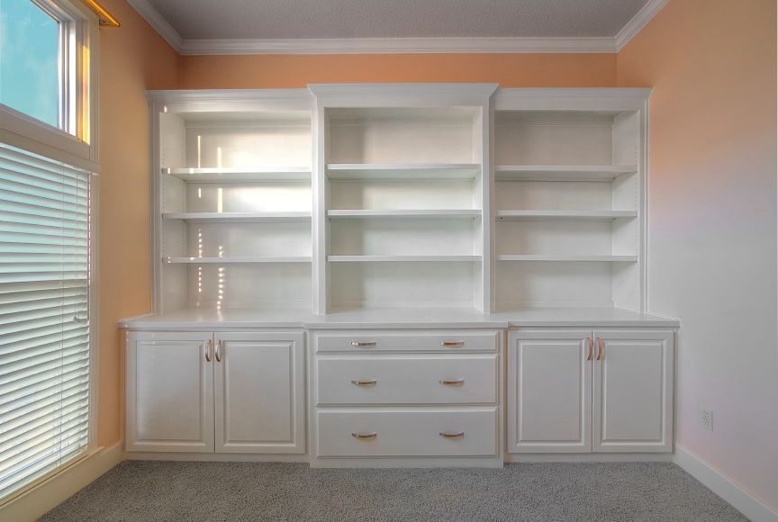 A room with a lot of shelves and drawers and a window