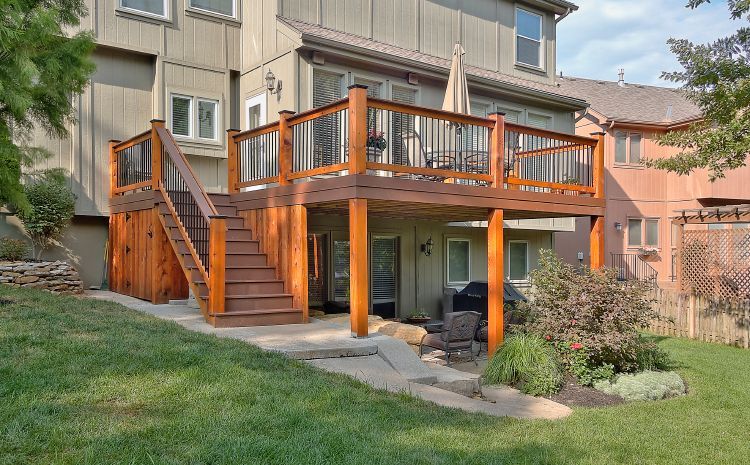 A large wooden deck with stairs is in the backyard of a house.
