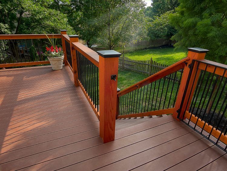 A wooden deck with a metal railing and stairs leading up to it.