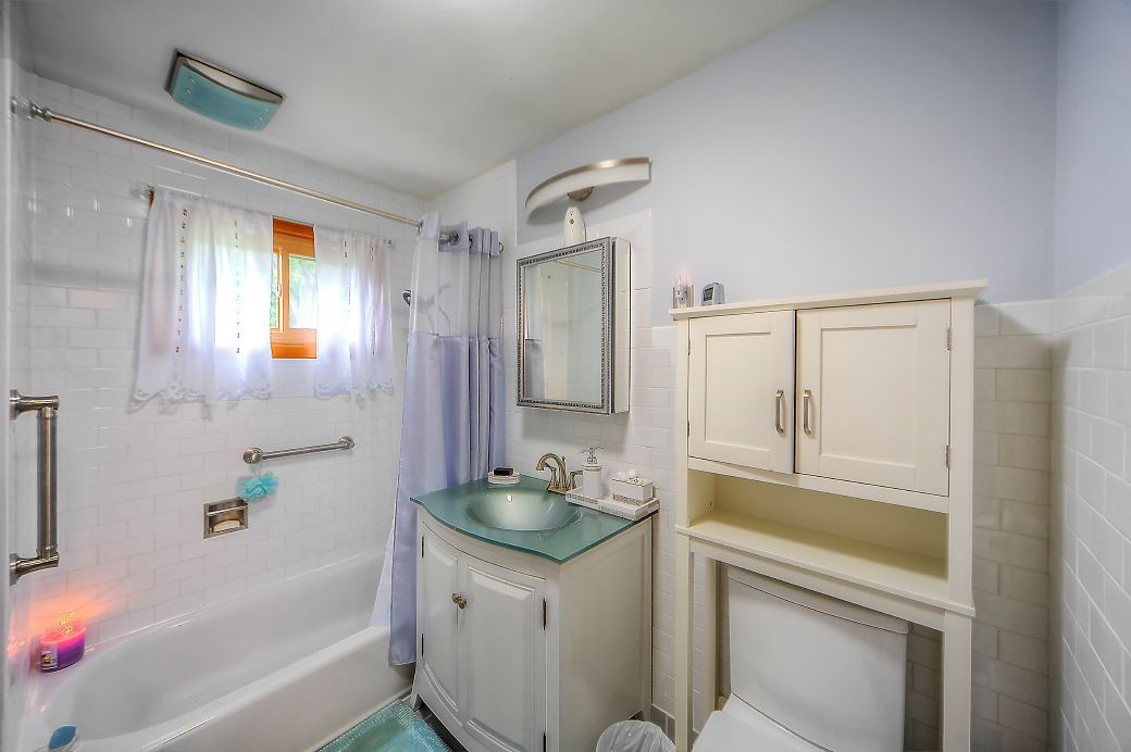 A bathroom with a sink , toilet , tub and mirror.