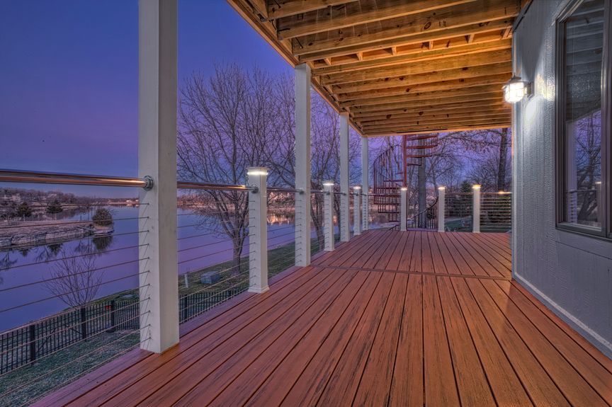 A large wooden deck with a view of a lake at night.