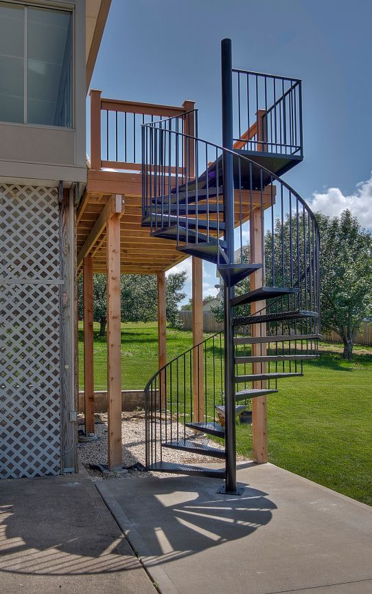 A spiral staircase leading up to a deck on the side of a house.
