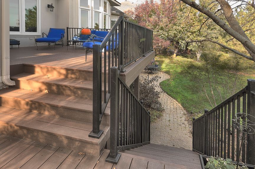 A wooden deck with stairs leading up to it and a metal railing.
