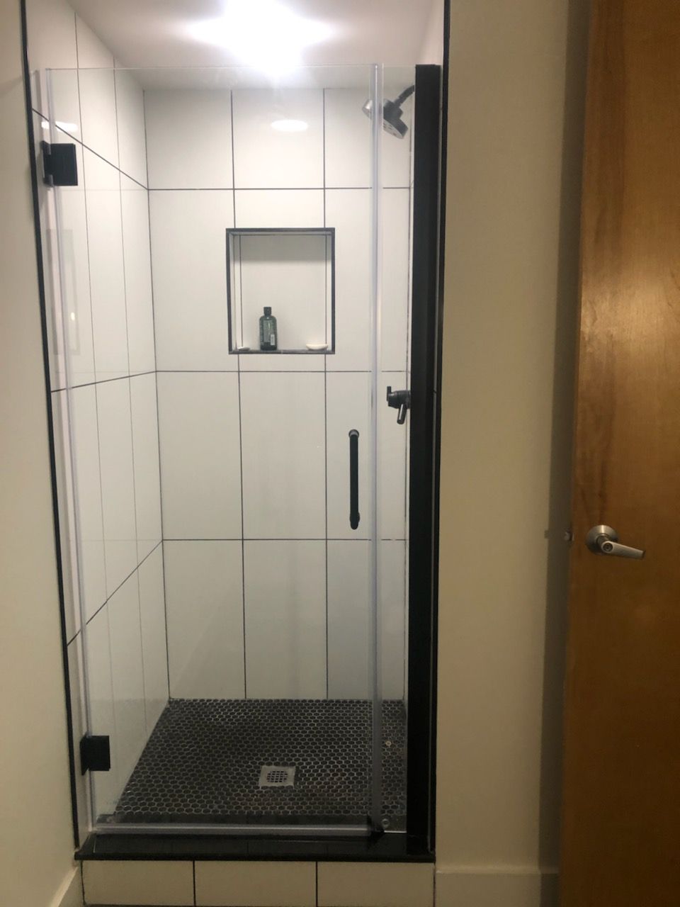 A bathroom with a walk in shower with a glass door.