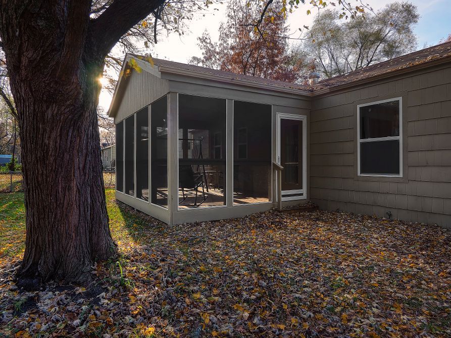 There is a screened in porch in the backyard of a house.