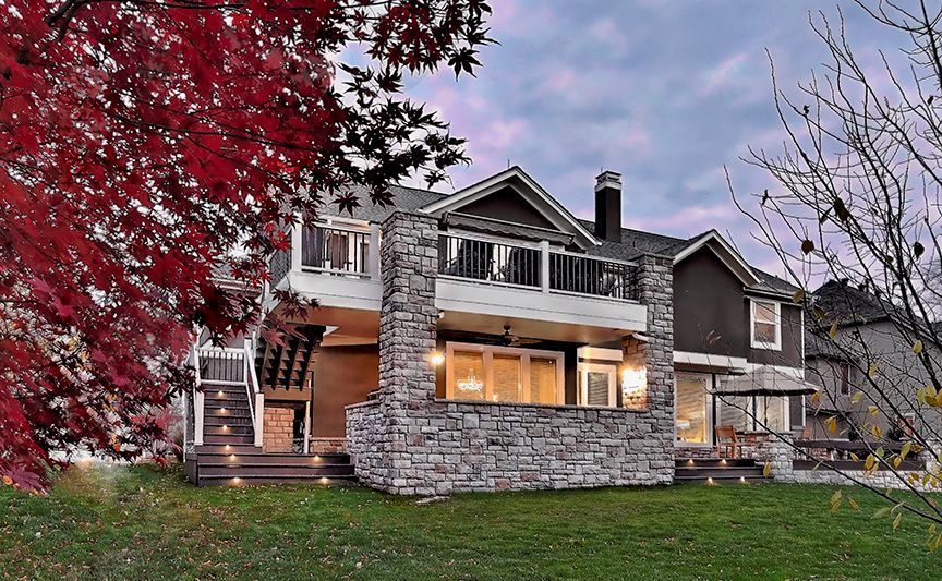 The back of a house with a stone wall and a large deck.