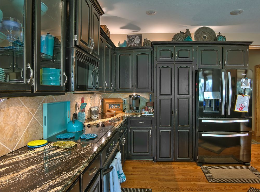 A kitchen with black cabinets and stainless steel appliances